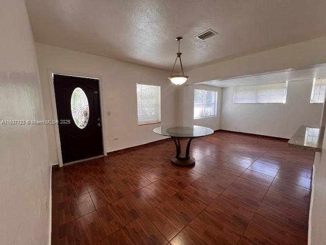 foyer entrance with baseboards, visible vents, and wood finished floors