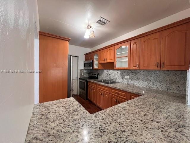 kitchen featuring brown cabinets, visible vents, backsplash, appliances with stainless steel finishes, and a sink