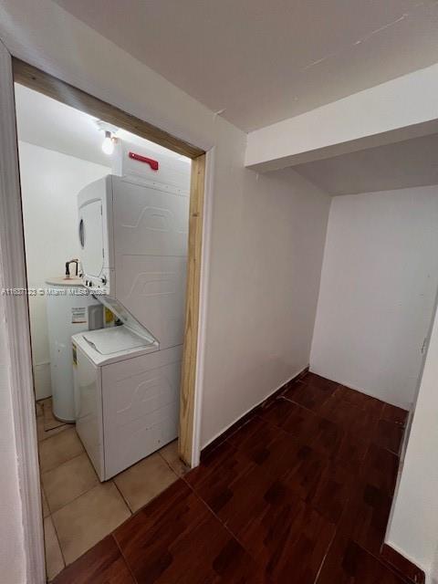 washroom featuring laundry area, light wood finished floors, stacked washer / dryer, and electric water heater