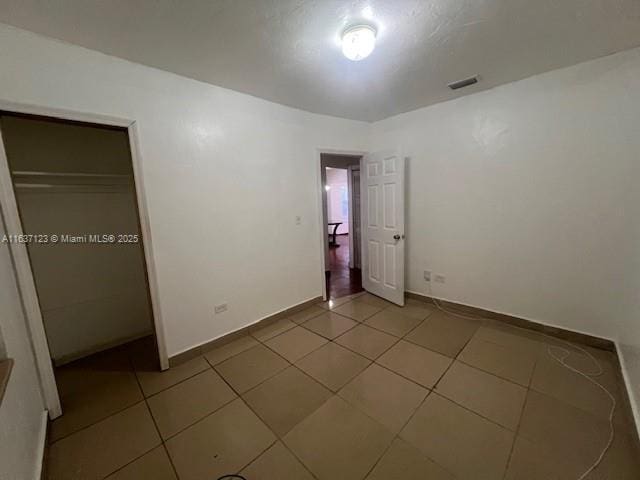 unfurnished bedroom featuring baseboards, visible vents, and tile patterned floors