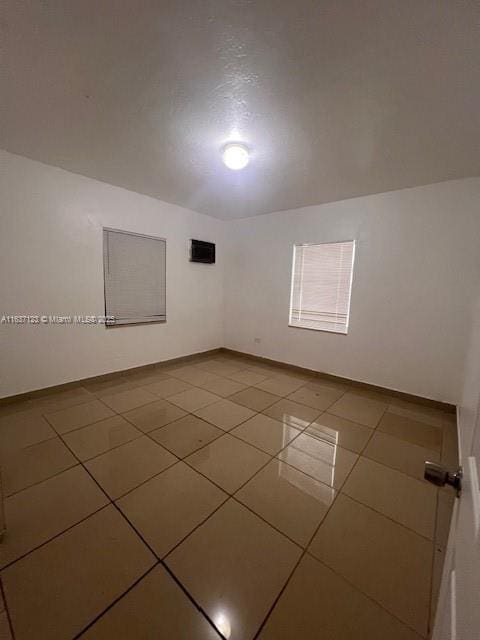 tiled empty room featuring baseboards