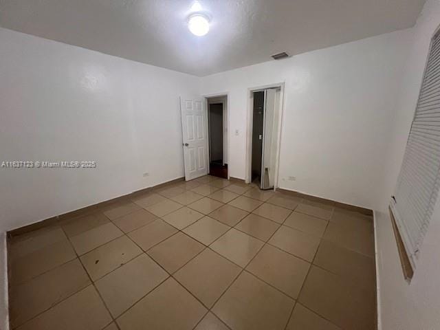 spare room with visible vents, baseboards, and light tile patterned floors