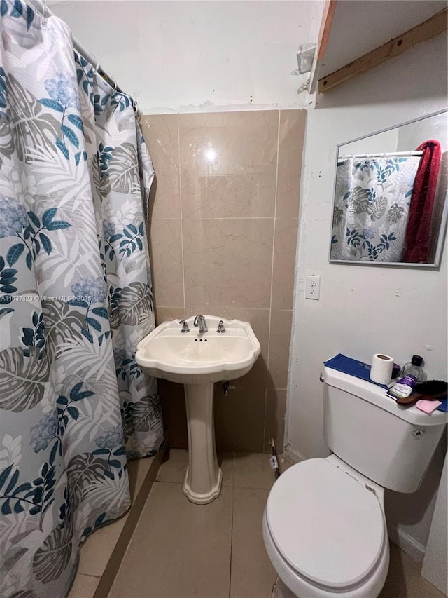 full bath featuring a shower with shower curtain, tile walls, toilet, and tile patterned floors