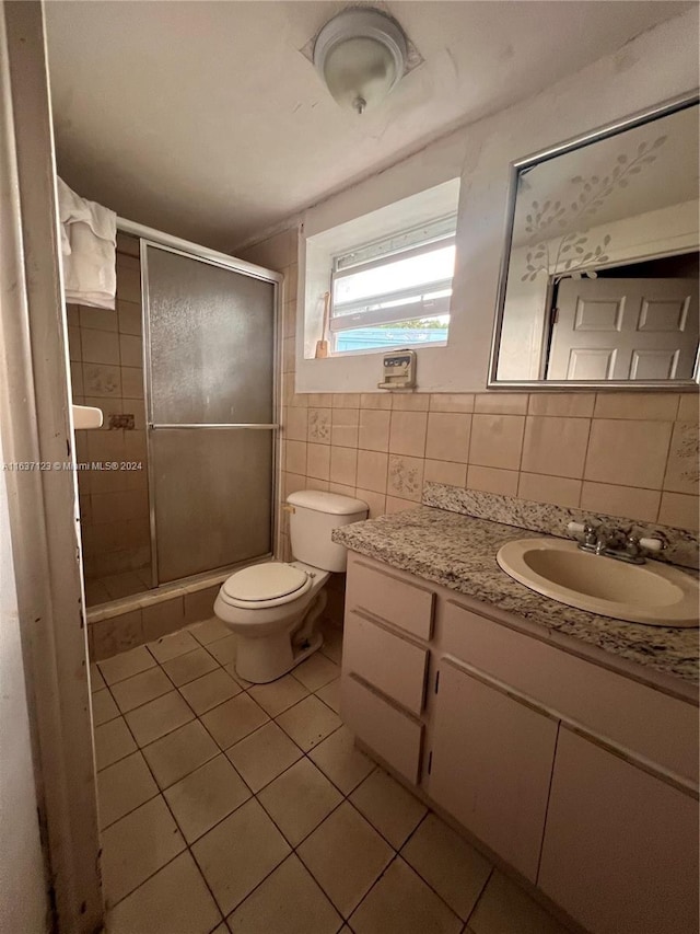 bathroom featuring tile walls, tile patterned floors, vanity, an enclosed shower, and toilet