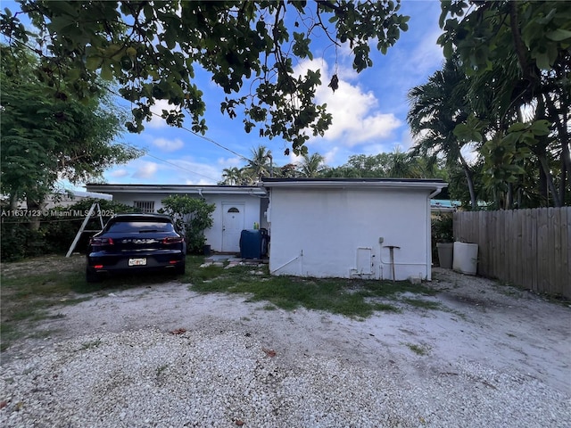 garage with gravel driveway and fence