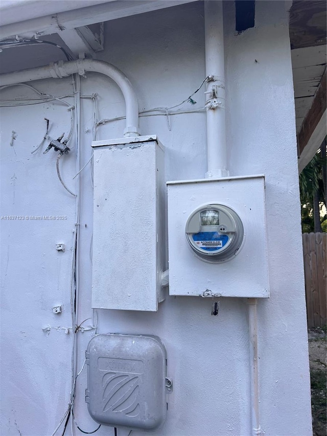 exterior details featuring fence, electric meter, and stucco siding