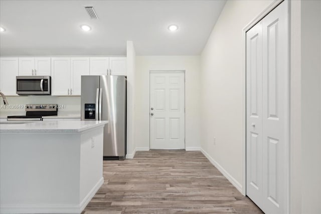 kitchen featuring appliances with stainless steel finishes, light hardwood / wood-style floors, and white cabinetry