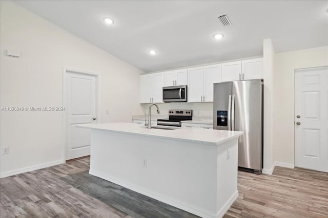 kitchen featuring appliances with stainless steel finishes, vaulted ceiling, light hardwood / wood-style floors, an island with sink, and sink