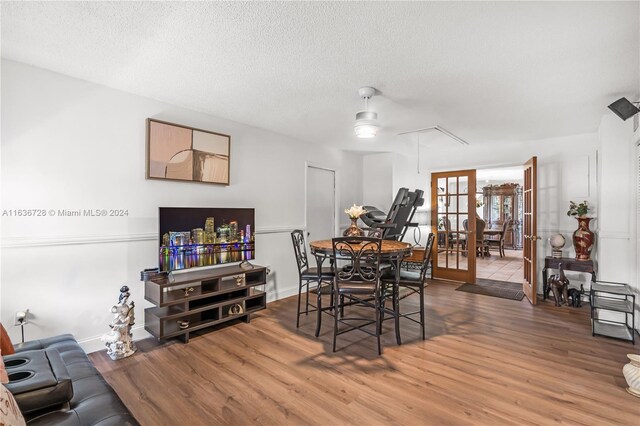 dining area with ceiling fan, wood-type flooring, french doors, and a textured ceiling