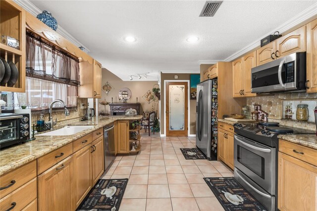 kitchen with sink, backsplash, appliances with stainless steel finishes, and light stone countertops