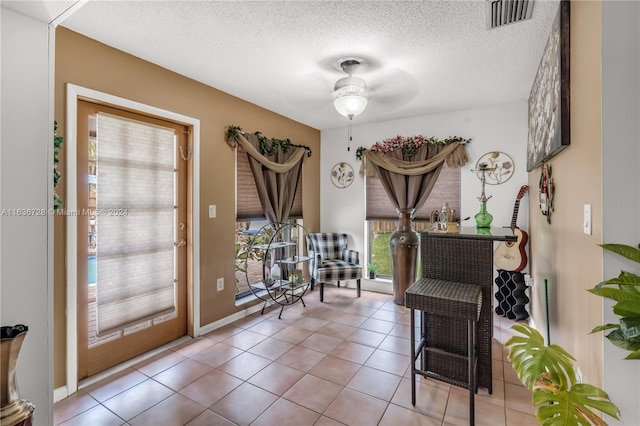 interior space with tile patterned flooring, ceiling fan, and a textured ceiling