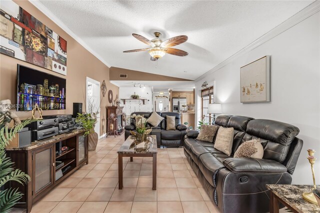 living room with ornamental molding, a textured ceiling, lofted ceiling, light tile patterned floors, and ceiling fan