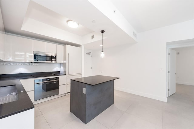 kitchen featuring light tile patterned flooring, white cabinetry, appliances with stainless steel finishes, decorative light fixtures, and a center island