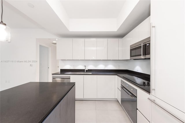 kitchen featuring black appliances, light tile patterned floors, hanging light fixtures, sink, and white cabinets