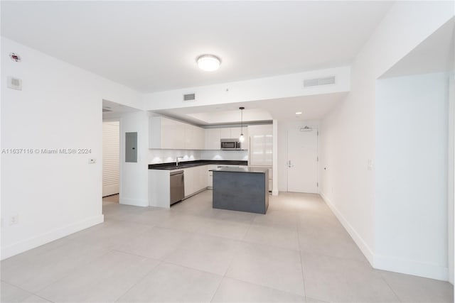 kitchen featuring electric panel, stainless steel appliances, hanging light fixtures, white cabinets, and a center island