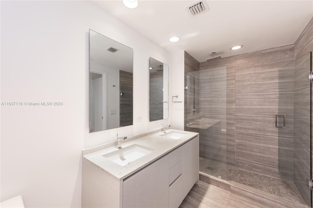 bathroom with a shower with shower door and vanity