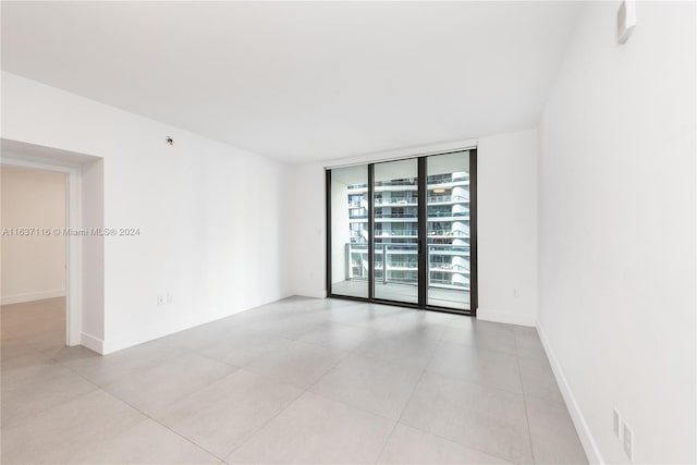 tiled empty room featuring floor to ceiling windows