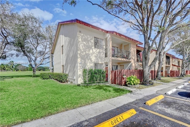 exterior space with stucco siding, uncovered parking, and a front yard