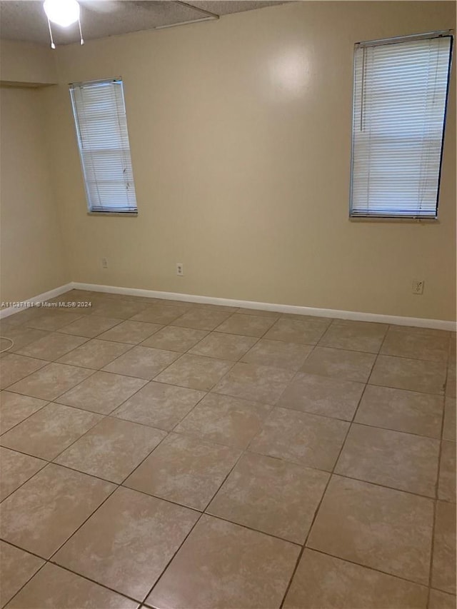 tiled spare room featuring ceiling fan