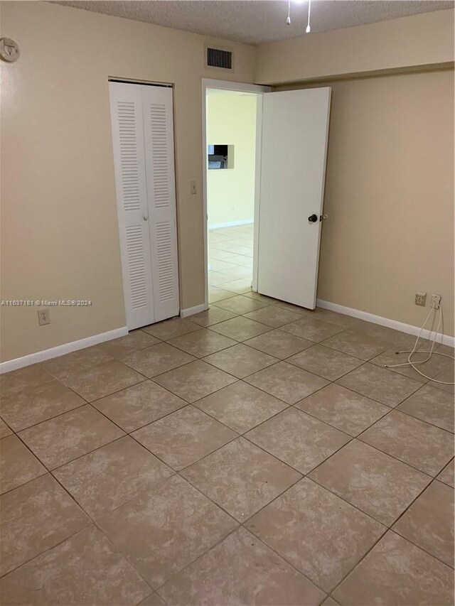 unfurnished room with light tile patterned flooring and a textured ceiling