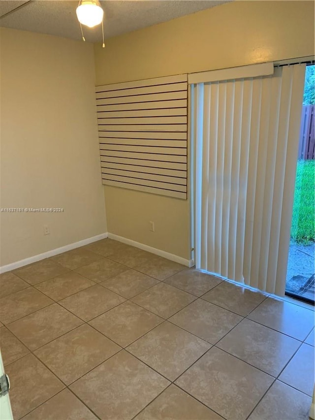 empty room featuring tile patterned flooring, a textured ceiling, and ceiling fan