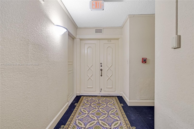 doorway to outside with a textured ceiling