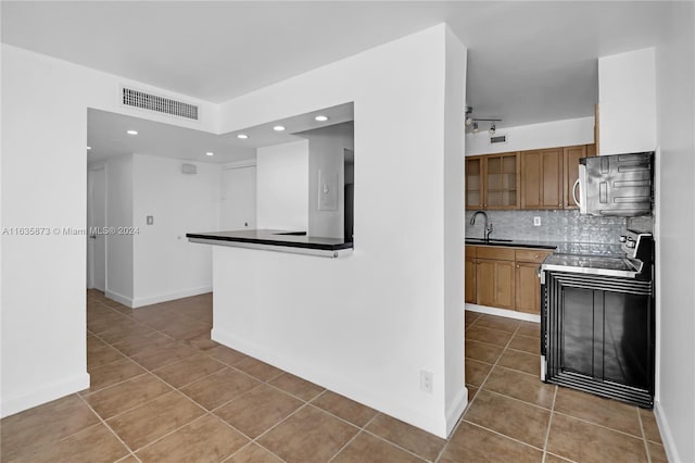 kitchen with electric stove, light tile patterned floors, decorative backsplash, sink, and kitchen peninsula