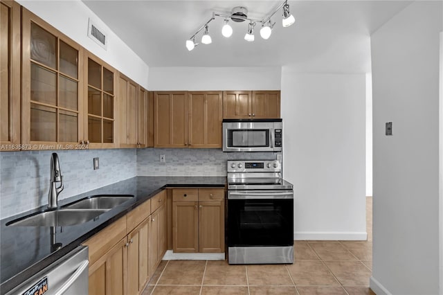 kitchen featuring appliances with stainless steel finishes, backsplash, track lighting, and light tile patterned floors