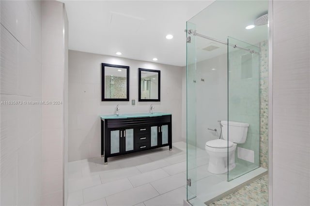 bathroom featuring toilet, tile walls, tile patterned floors, a shower with door, and vanity