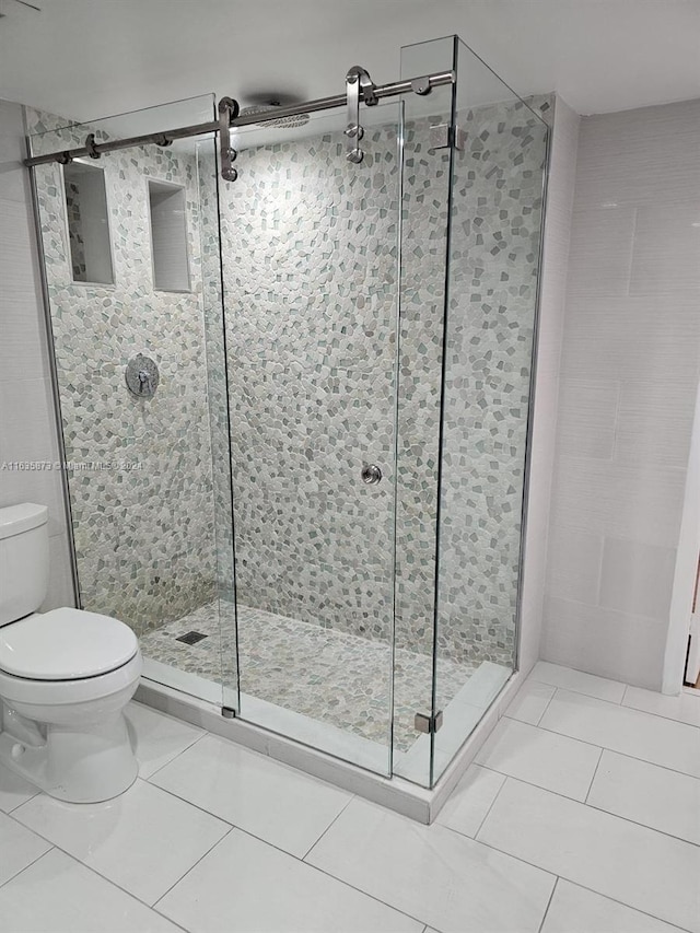 bathroom featuring a shower with door, toilet, and tile patterned flooring