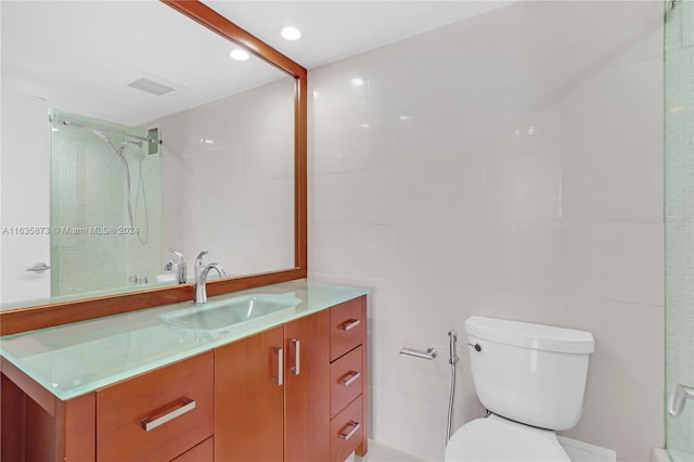 bathroom with vanity, tile walls, a tile shower, and toilet