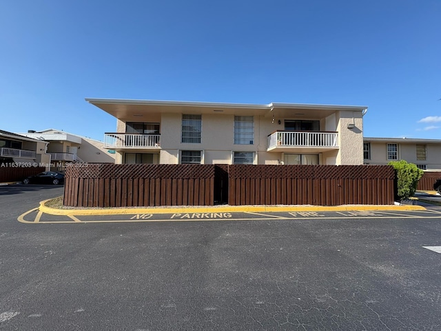 view of front of property featuring uncovered parking, stucco siding, and a balcony