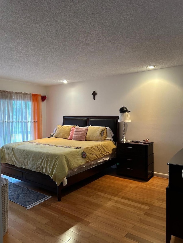 bedroom with a textured ceiling and light wood-type flooring