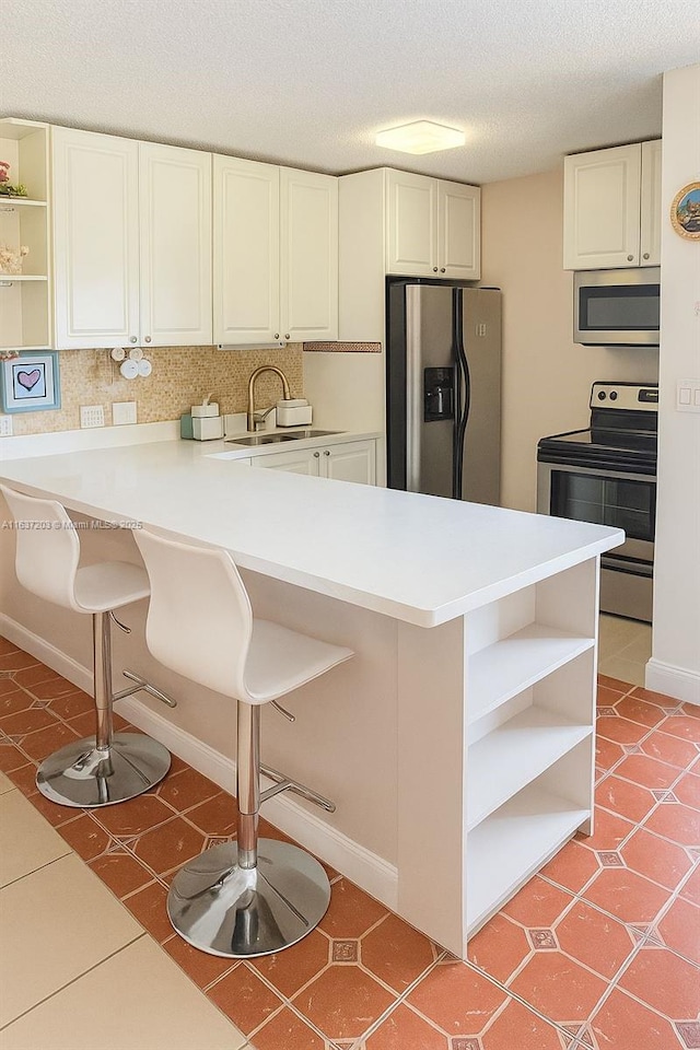 13781 SW 66th St Unit 221B, Miami, FL 33183 - kitchen with appliances with stainless steel finishes, open shelves, a peninsula, a breakfast bar area, and light tile patterned floors