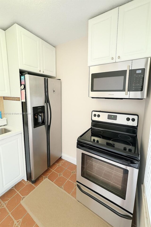13781 SW 66th St Unit 221B, Miami, FL 33183 - kitchen with stainless steel appliances, tile patterned flooring, white cabinetry, and light countertops