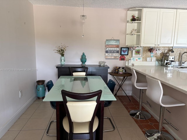 dining area with light tile patterned floors, baseboards, and a textured ceiling