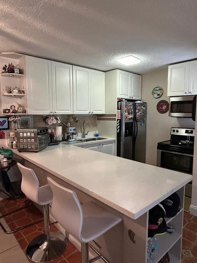 kitchen featuring sink, white cabinetry, a textured ceiling, kitchen peninsula, and appliances with stainless steel finishes