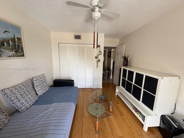 living room with visible vents, a textured ceiling, ceiling fan, and wood finished floors