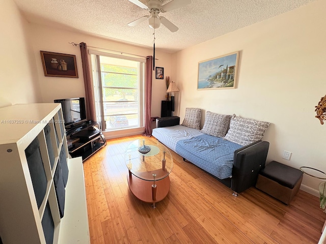 living area with a ceiling fan, a textured ceiling, and light wood finished floors