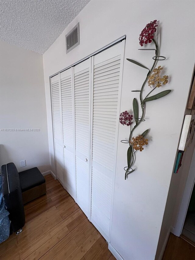 details featuring a textured ceiling, visible vents, and wood finished floors