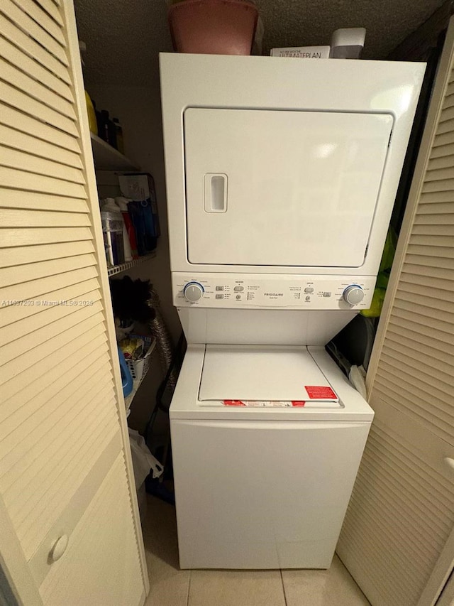 washroom featuring stacked washer and dryer, laundry area, and light tile patterned floors
