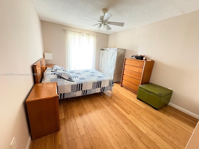 bedroom with light wood-style floors, a ceiling fan, a textured ceiling, and baseboards