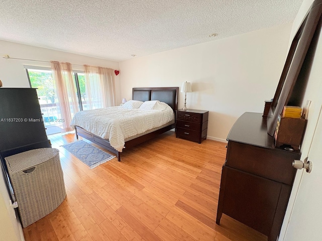 bedroom with a textured ceiling, access to exterior, and light wood-style floors