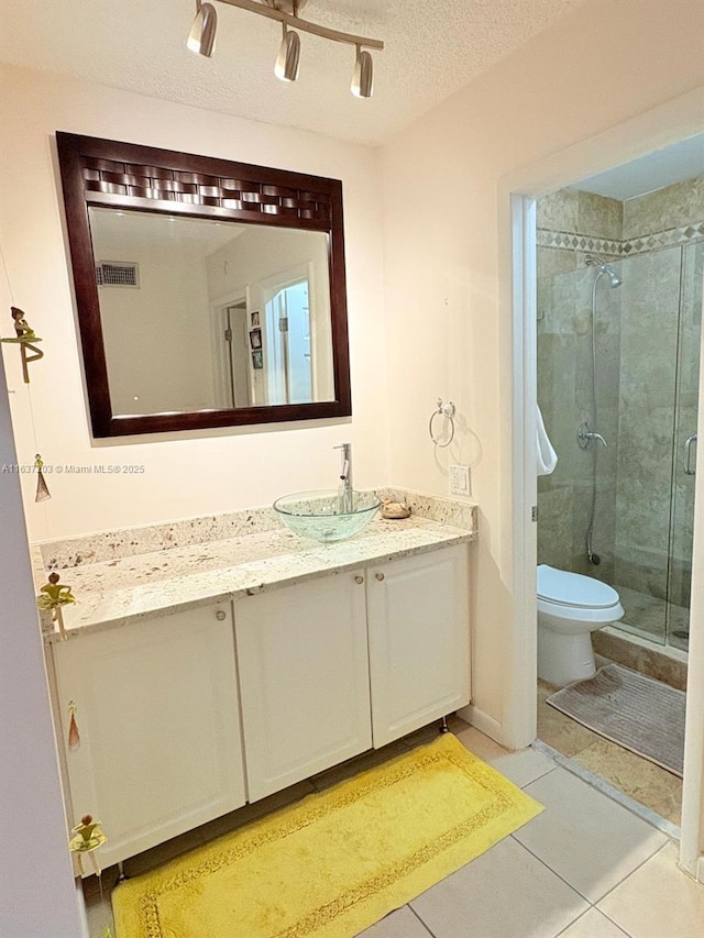 full bath with tile patterned flooring, vanity, toilet, a shower stall, and visible vents