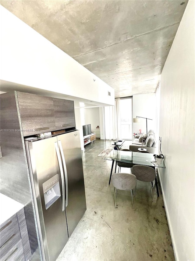 kitchen featuring concrete flooring and stainless steel fridge