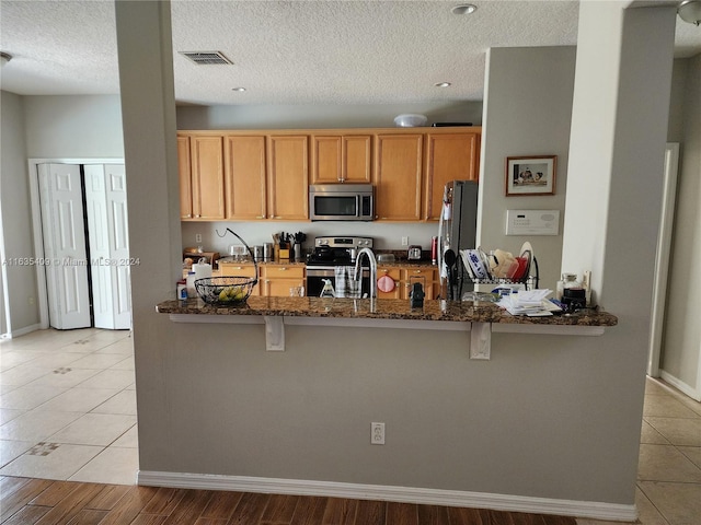 kitchen with dark stone counters, stainless steel appliances, and light tile patterned floors