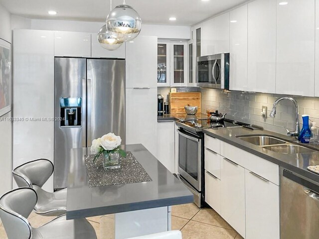 kitchen with white cabinetry, tasteful backsplash, light tile patterned floors, appliances with stainless steel finishes, and sink