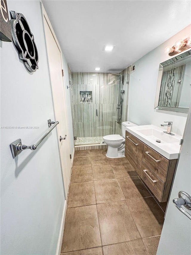 bathroom with vanity, a shower with shower door, tile patterned floors, and toilet