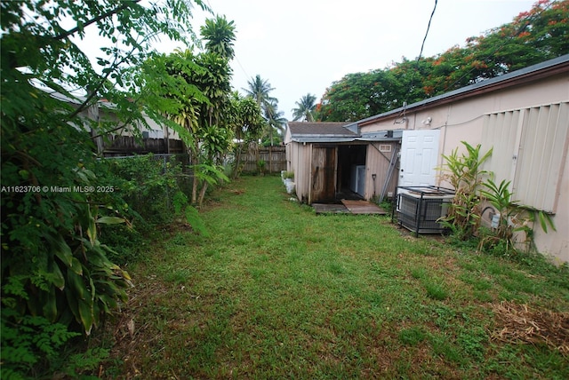 1801 NE 176th St, North Miami Beach, FL 33162 - view of yard featuring a fenced backyard, a storage unit, an outbuilding, and central AC