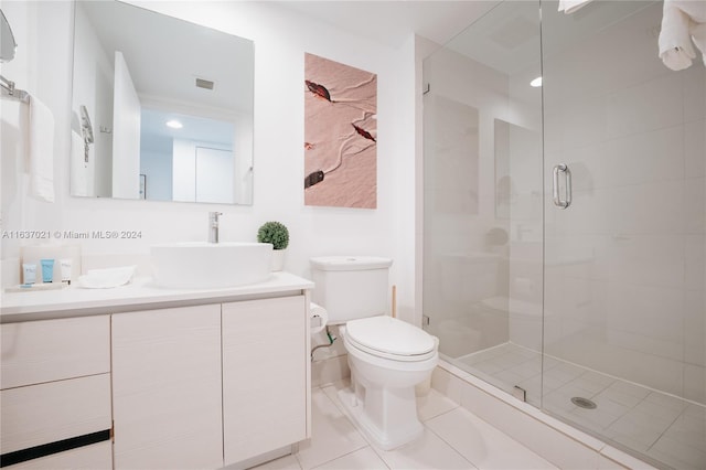 bathroom featuring vanity, a shower with door, tile patterned flooring, and toilet